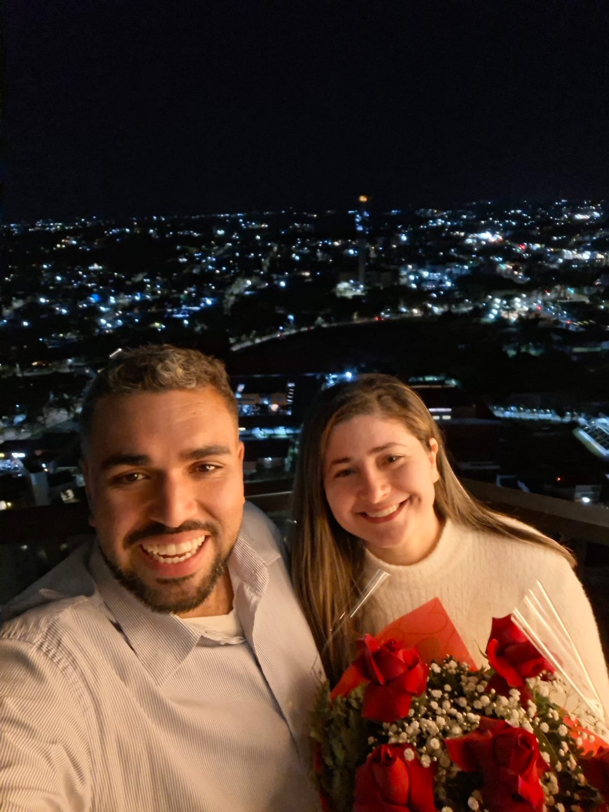 Selfie noturna do casal com buquê